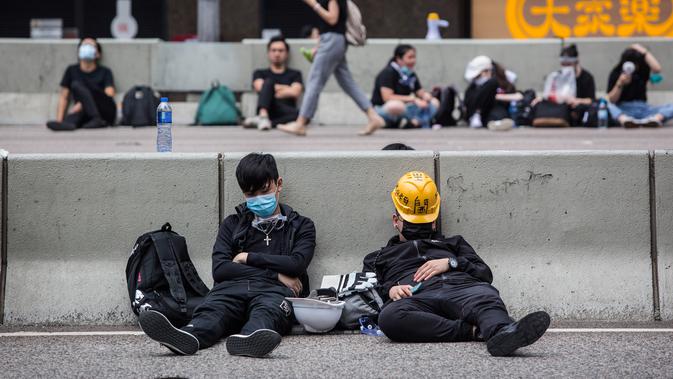 Sejumlah pengunjuk rasa tidur di jalanan utama dekat Gedung Dewan Legislatif saat menggelar protes terkait RUU Ekstradisi di Hong Kong, Senin (17/6/2019). Pengunjuk rasa menuntut kepala eksekutif Hong Kong, Carrie Lam, mundur dari jabatannya terkait RUU Ekstradisi. (ISAAC LAWRENCE/AFP)