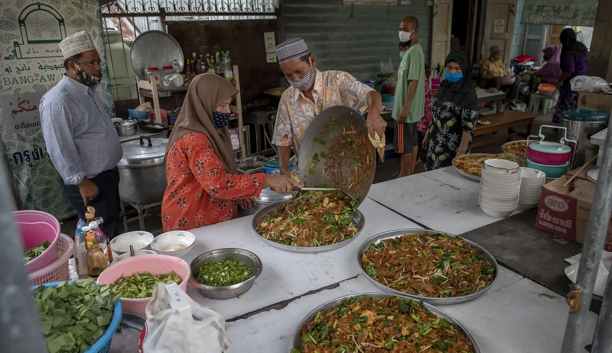 Sekretaris Masjid Bang Aw, Adul Yothasmutr (kiri) menyaksikan sukarelawan menyiapkan makanan di Bangkok, Thailand, Kamis (30/4/2020). Setiap hari selama Ramadan, sukarelawan membagikan makanan kepada 150 keluarga sekitar Masjid Bang Aw. (AP Photo/Gemunu Amarasinghe)