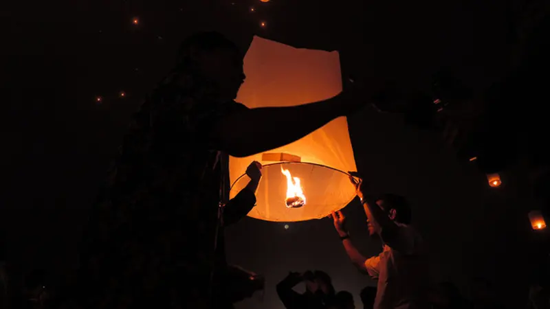 Candi Borobudur dengan latar belakang langit malam yang gelap dihiasi oleh ribuan titik-titik cahaya oranye dari lampion.