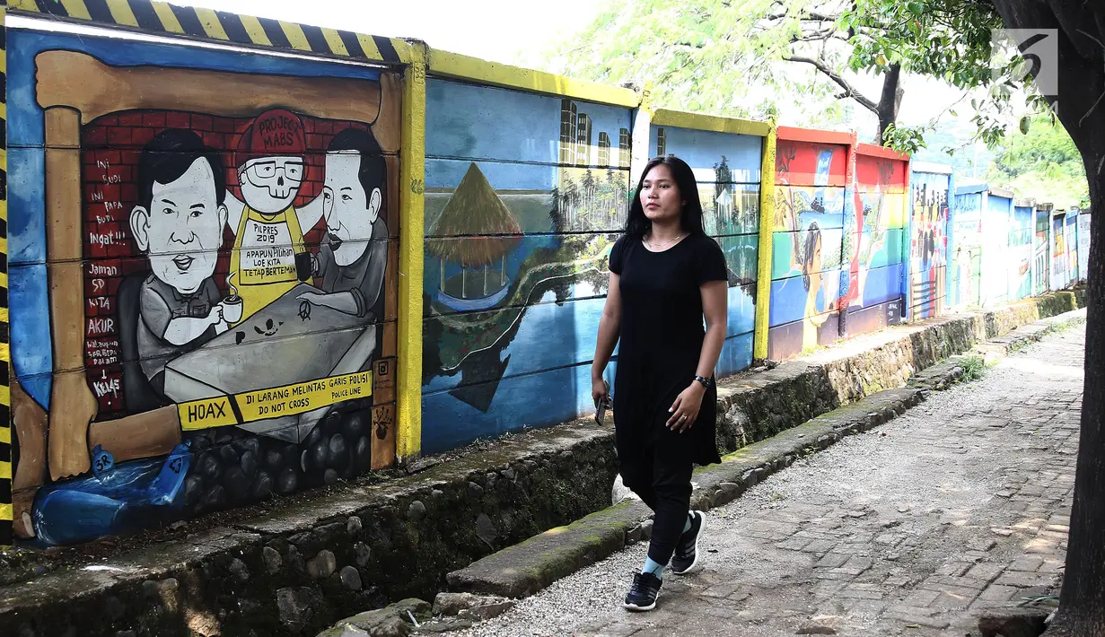 Warga melintas di dekat mural Capres Joko Widodo dan Prabowo Subianto di Jalan Juanda, Depok, Jabar, Rabu (21/11). Mural tersebut memiliki pesan agar masyarakat tetap damai dan berteman meski berbeda memilih Capres. (Liputan6.com/Herman Zakharia)