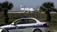 Mobil polisi disiagakan di dekat pesawat milik maskapai Mesir, EgyptAir, yang dibajak dan dipaksa mendarat di Bandara Larnaca, Siprus, Selasa (29/3). Pembajak adalah seorang penumpang yang mengklaim membawa sabuk bahan peledak (REUTERS/Yiannis Kourtoglou)
