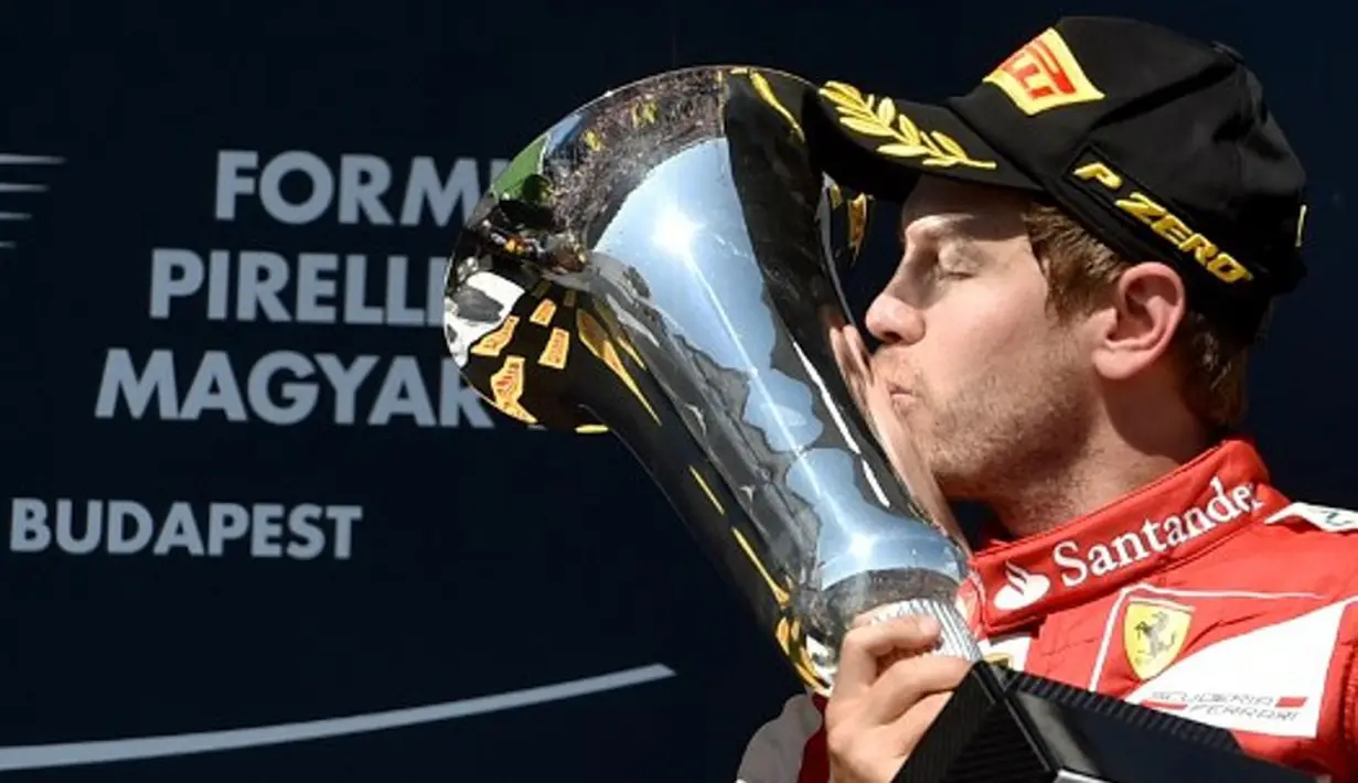 Pebalap Ferrari, Sebastian Vettel, mencium trofi juara F1 GP Seri Hungaria di Sirkuit Hungaroring, Budapest, Hungaria. (26/7/2015). (AFP PHOTO/Andrej Isakovic)