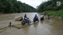 Sebuah rakit mengangkut motor dan warga menyeberangi Sungai Cisadane di Rumpin, Bogor, Selasa (13/3). Mereka terpaksa menaiki rakit akibat jembatan yang merupakan akses jalan utama Ciseeng -Rumpin masih dalam perbaikan. (Liputan6.com/Achmad Sudarno)
