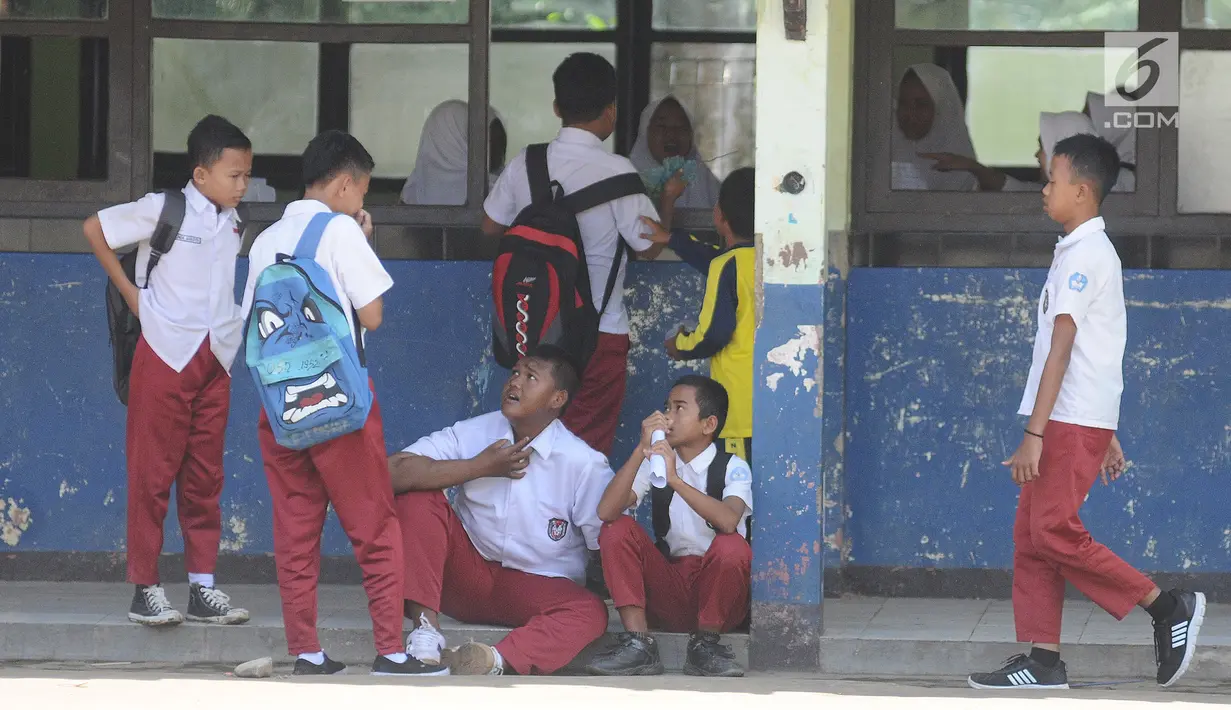 Arya Permana sedang berbincang bersama temannya  di SDN Cipurwasari 1 kawasan Karawang, Jawa Barat, Selasa (9/4). Arya Permana diketahui memiliki berat badan hingga 192 kg, sekarang sudah turun 105 kg menjadi 87 kg pasca operasi lambung. (Liputan6.com/Herman Zakharia)