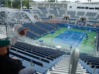 Penonton duduk menunggu penundaan pertandingan akibat hujan selama putaran pertama turnamen tenis AS Terbuka 2017 di Grandstand Stadium, New York (29/8). Meski hujan, para penonton tetap antusias. (AP Photo / Andres Kudacki)