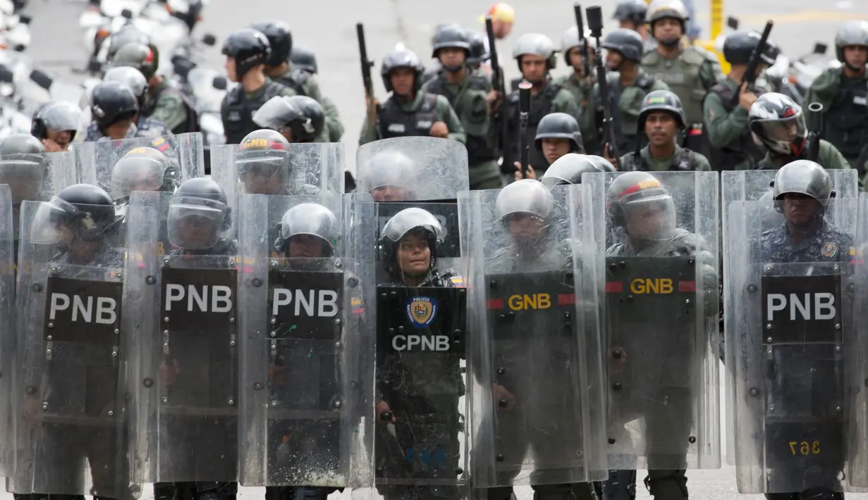 Polisi antihuru-hara berjaga selama unjuk  rasa mahasiswa Venezuela Central University, Caracas, Venezuela (21/11). Mereka Menuntut peningkatan anggaran beasiswa dan membuka kembali kafetaria universitas. (AP Photo/Ariana Cubillos)