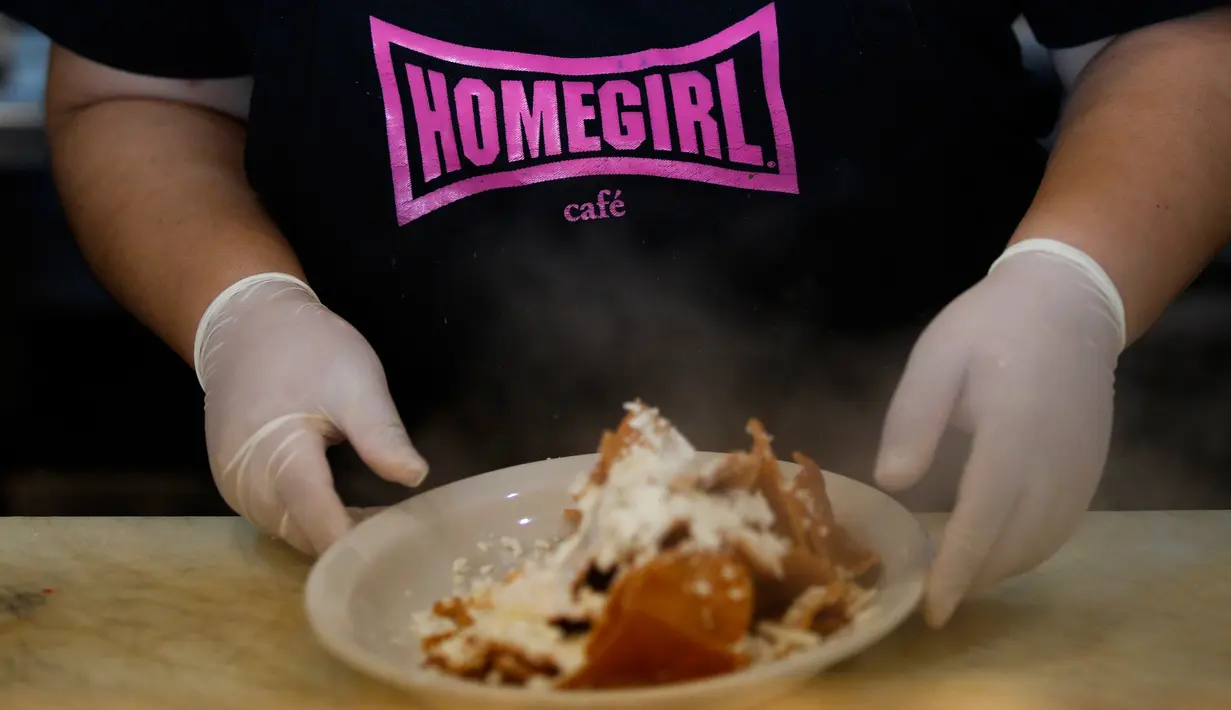 Elvia Hernandez (30) menyiapkan menu makanan di dapur Homegirl Cafe, Los Angeles, Senin (16/7). Para mantan anggota geng ini juga sering berbagi cerita pada pengunjung tentang pengalaman mereka mendapatkan kehidupan yang lebih baik. (AP/Jae C. Hong)