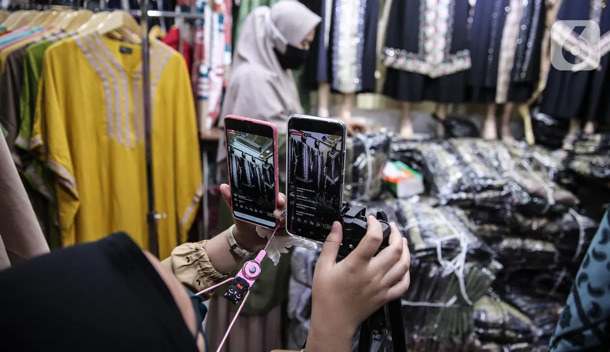 Pedagang menunjukkan sejumlah pakaian melalui aplikasi online (daring) di Pasar Tanah Abang, Jakarta, Rabu (1/7/2020). Pedagang Pasar Tanah Abang mulai menjual barang secara daring untuk menambah penjualan dan mengantisipasi turunnya jumlah pembeli di masa PSBB Transisi. (Liputan6.com/Faizal Fanani)