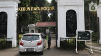 Petugas keamanan memeriksa pengunjung di Kebun Raya Bogor, Jawa Barat, Selasa (7/7/2020). Kebun Raya Bogor menerapkan pemesanan tiket secara daring serta kapasitas pengunjung dibatasi hanya 50 persen. (Liputan6.com/Herman Zakharia)