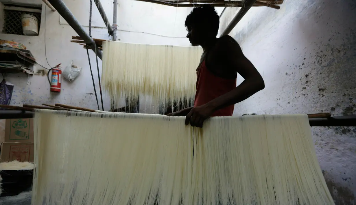 Pekerja India menggantung helai bihun untuk dikeringkan di sebuah pabrik di Ahmadabad pada 16 Mei 2019. Bihun sangat diminati di kalangan muslim India karena merupakan menu favorit yang kerap disuguhkan saat berbuka puasa bersama dengan buah-buahan manis. (AP Photo/Ajit Solanki)