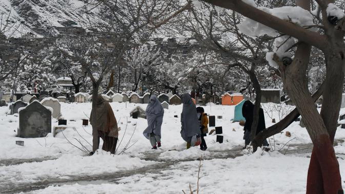 CUACA BURUK DI PAKISTAN DAN AFGHANISTAN - Sejumlah orang berjalan melewati makam usai hujan salju lebat di Quetta, Pakistan, Senin (13/1/2020). Cuaca buruk berupa hujan salju lebat, hujan, dan banjir bandang melanda Pakistan dan Afghanistan. (Banaras KHAN/AFP)