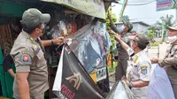 Anggota Satpol PP Kota Depok melakukan penertiban spanduk produk rokok di warung penjual rokok di Kota Depok, Selasa (24/8/2021). (Liputan6.com/Dicky Agung Prihanto)