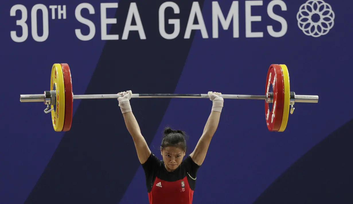 Lifter Windy Aisyah melakukan angkatan saat SEA Games 2019 cabang angkat besi nomor 49 kg di Stadion Rizal Memorial, Manila, Minggu (1/12). Dirinya meraih emas dengan total angkatan 104 kg. (Bola.com/M Iqbal Ichsan)
