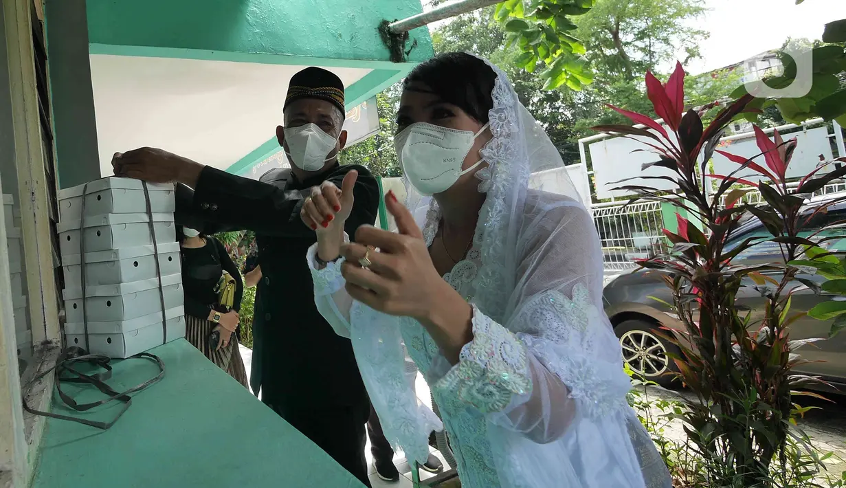 Pasangan Ririn  dan Zaenal saat melangsungkan pernikahan di KUA Kecamatan Matraman, Jakarta, Selasa (22/02/2022). Sejumlah pasangan sengaja melangsungkan pernikahan pada hari ini yang memiliki tanggal, bulan, dan tahun unik yakni 22-02-2022. (Liputan6.com/Herman Zakharia)