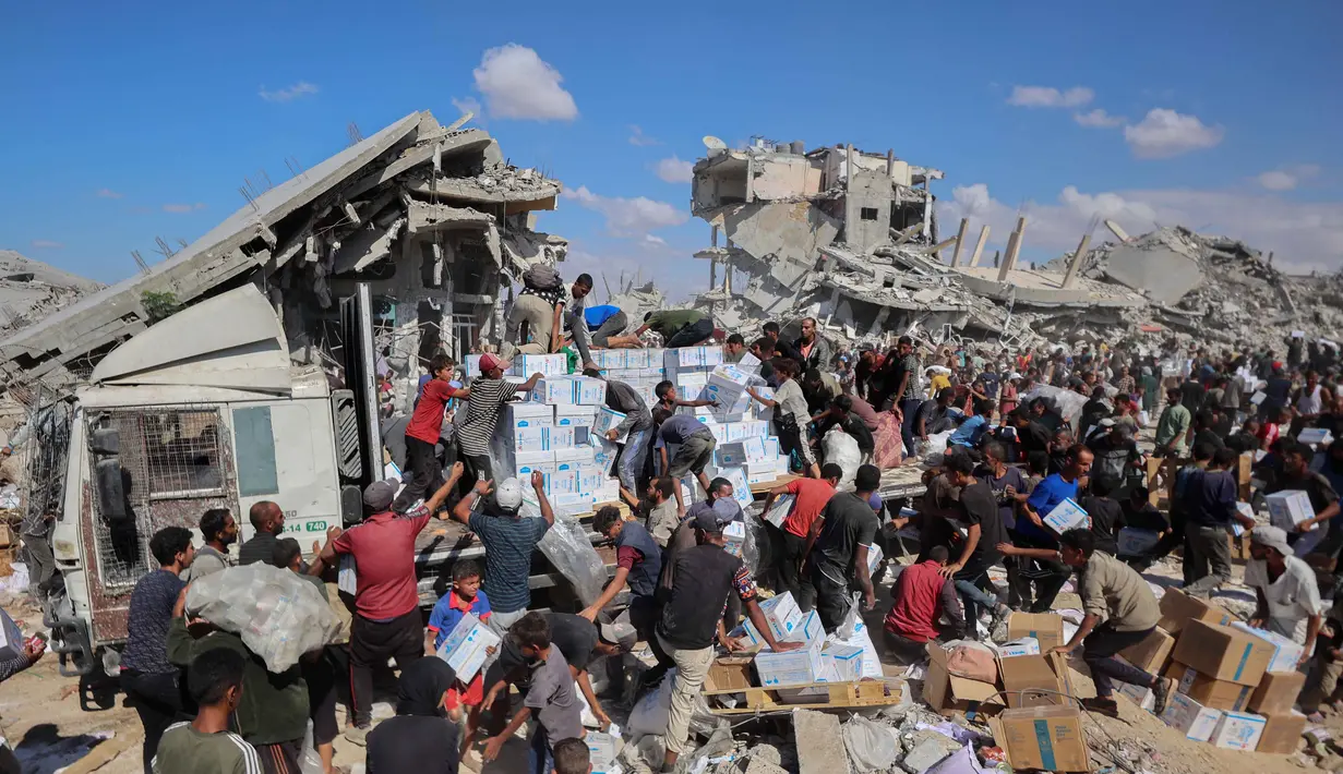 Penduduk Palestina berkumpul di sekitar truk bantuan yang masuk melalui pos perbatasan Karem Abu Salem di Khan Yunis, bagian selatan Jalur Gaza, pada 12 Oktober 2025. (Omar AL-QATTAA/AFP)