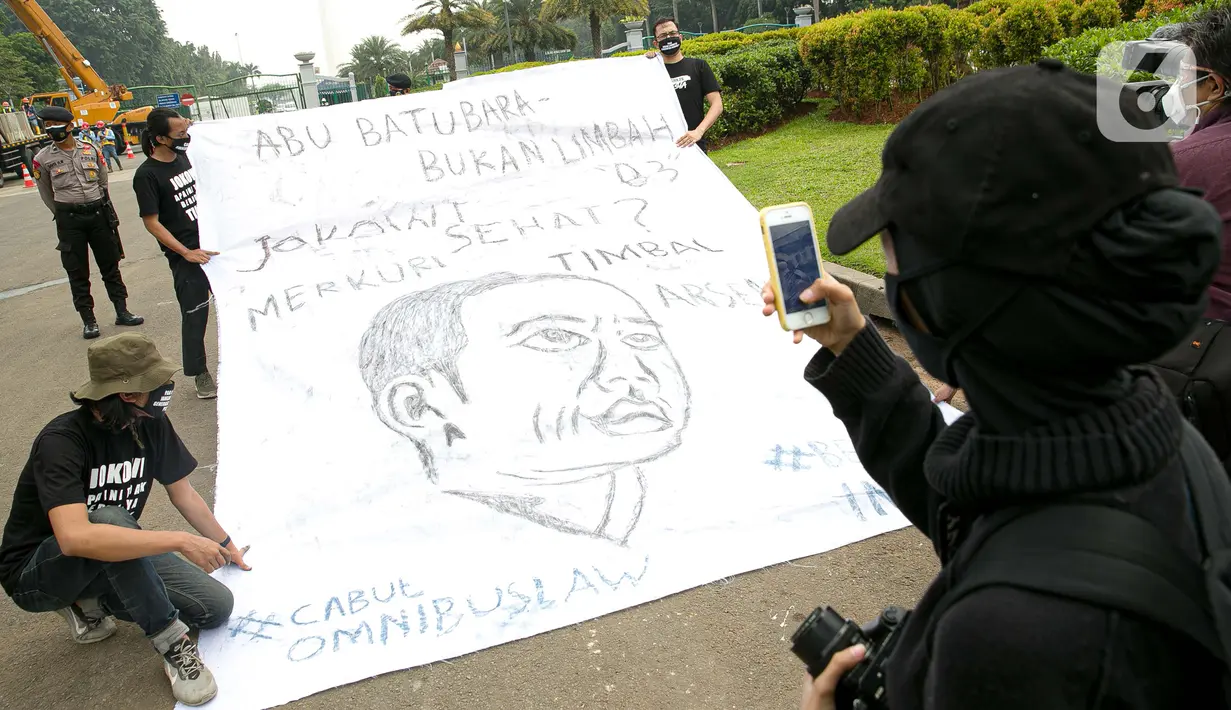 Sejumlah aktivis melakukan aksi simbolik di kawasan Patung Kuda, Jakarta, Kamis (18/3/2021). Aktivis menuntut Presiden Joko Widodo untuk mencabut Omnibus Law UU Cipta Kerja dan regulasi turunannya yang menghapus Fly Ash Bottom Ash (FABA) dari daftar limbah B3. (Liputan6.com/Faizal Fanani)