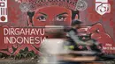Pengendara motor melintasi mural bertema HUT ke-75 RI di Jalan Abdullah Syafei, Jakarta, Minggu (16/8/2020). Jelang HUT ke-75 RI, mural bernuansa Merah Putih banyak menghiasi jalanan Ibu Kota guna memberi semangat nasionalisme kepada warga di tengah pandemi COVID-19. (merdeka.com/Iqbal S.Nugroho)