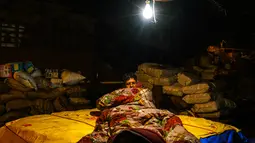 Seorang pria tertidur di dekat tumpukan barang di kawasan tua New Delhi, India (6/3). Akan tetapi, predikat itu dicopot karena masalah krisis uang tunai yang terjadi di negara tersebut. (AFP Photo/Chandan Khanna)