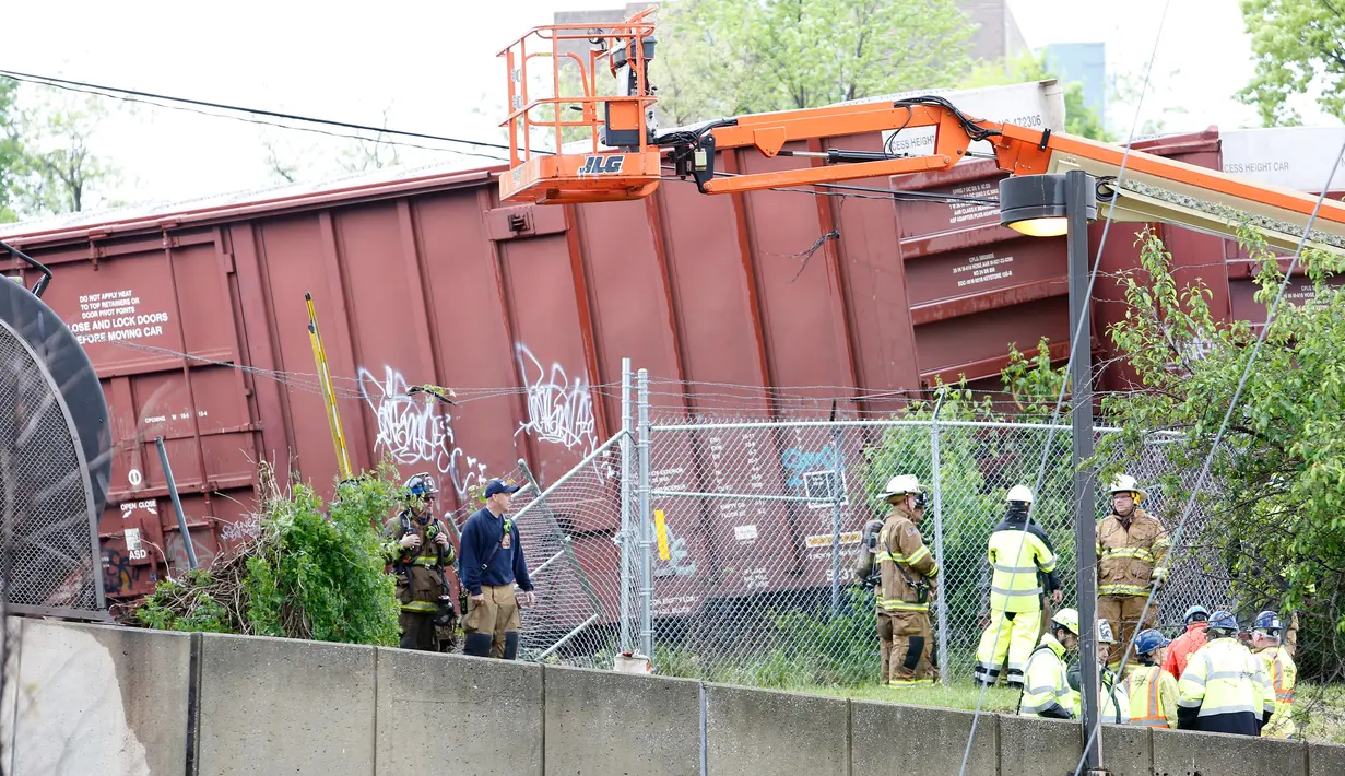 Petugas memeriksa lokasi anjloknya kereta barang CSX hingga keluar dari rel di dekat stasiun kereta komuter Washington, AS, Minggu (1/5). Kereta ini menumpahkan zat kimia berbahaya dan mengganggu lalu lintas kereta api bawah tanah. (Andrew BIRAJ /AFP)