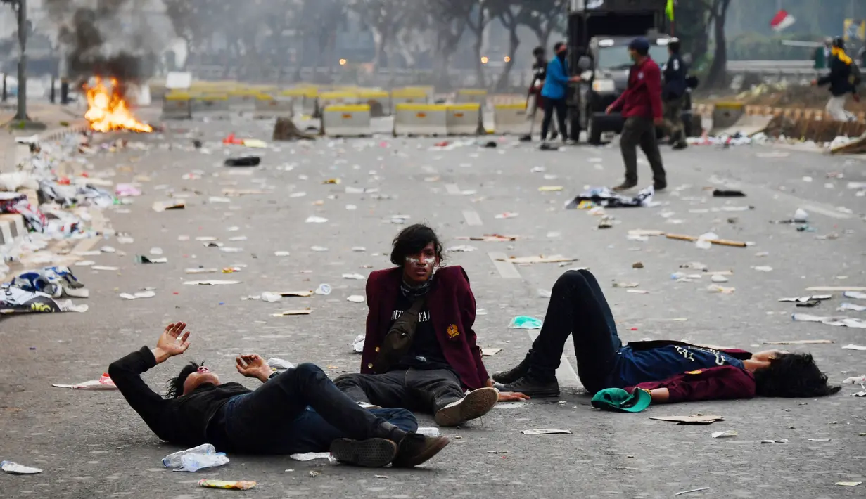 Sejumlah mahasiswa terkapar setelah polisi menembakkan gas air mata dalam demonstrasi menolak pengesahan RUU KUHP dan revisi UU KPK di depan Gedung DPR, Jakarta, Selasa (24/9/2019). Sejumlah mahasiswa tumbang setelah polisi menembakkan gas air mata untuk membubarkan demonstrasi. (ADEK BERRY/AFP)