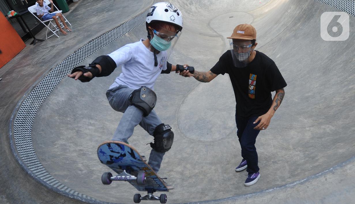 Instruktur melatih seorang anak menggunakan skateboard dengan memakai masker dan face shield di Crooz Shophouse di kawasan Duren Tiga, Jakarta Selatan, Minggu (2/8/2020). Mereka kembali melakukan latihan seminggu dua kali dengan menerapkan protokol kesehatan. (merdeka.com/Arie Basuki)