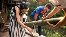 Pegawai menuangkan minuman beralkohol ke gelas untuk dinikmati setelah beberapa bulan disimpan di dalam batang bambu di Hutan Yibin, China pada 30 Juli 2016. (AFP Photo/Fred Dufour)