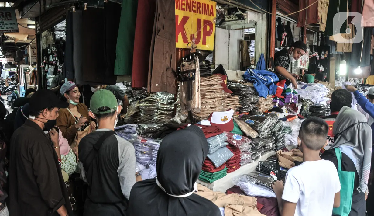 Pedagang melayani pembeli seragam sekolah di Pasar Mester Jatinegara, Jakarta Timur, Senin (3/1/2022). Salah satu pedagang mengungkapkan penjualan seragam sekolah mengalami peningkatan 50 persen seiring pemberlakuan PTM di Jakarta yang kembali digelar 100 persen. (merdeka.com/Iqbal S. Nugroho)