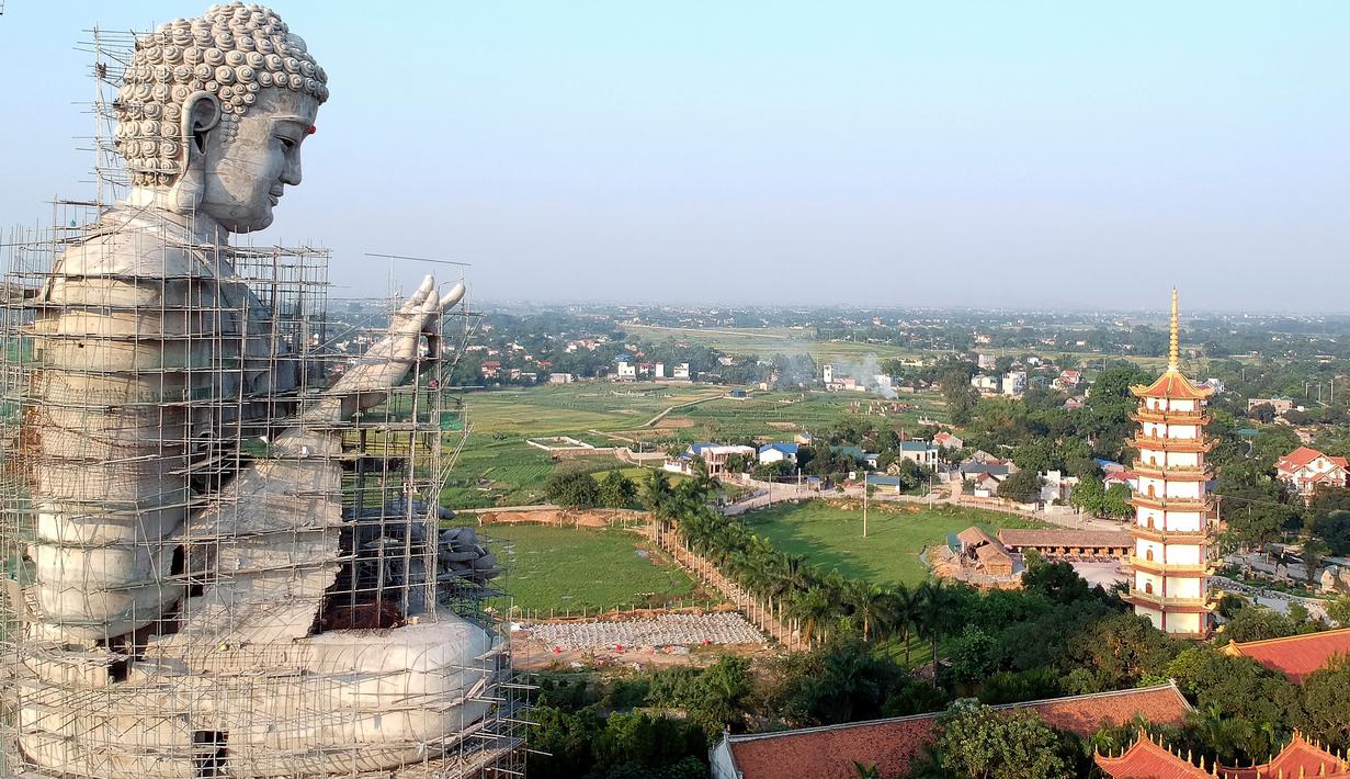 Foto udara pada 18 Mei 2019 memperlihatkan patung Buddha raksasa yang sedang dibangun di pagoda Khai Nguyen di distrik Son Tay, pinggiran Hanoi. Pengerjaan patung Buddha setinggi 72 meter ini dimulai pada 2015 dan diperkirakan selesai dalam lima tahun mendatang. (Photo by Manan VATSYAYANA/AFP)