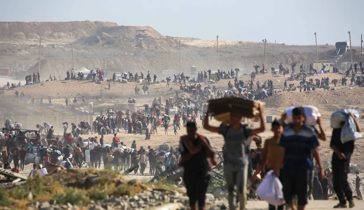 Orang-orang berjalan membawa tas-tas berisi bantuan kemanusiaan yang mereka terima di pusat distribusi yang dikelola oleh Yayasan Kemanusiaan Gaza (GHF) yang didukung Ameriks Serikat dan Israel, di koridor Netzarim, Nuseirat, Jalur Gaza tengah, pada 26 September 2025. (Eyad BABA/AFP)
