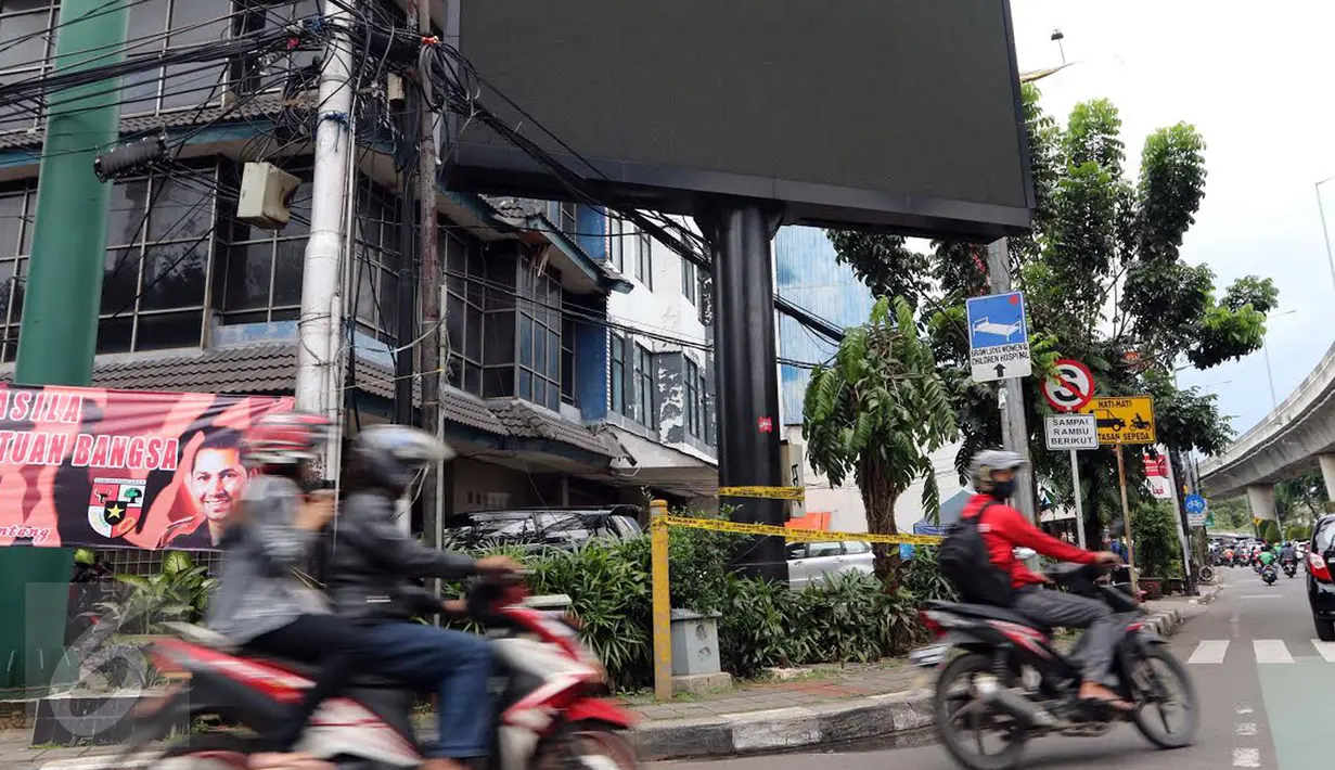 Pengendara motor melintas di depan sebuah videotron di simpang Jalan Iskandarsyah, Jakarta Selatan, Minggu (2/10). Garis polisi terpasang terkait insiden videotron yang memutar video porno pada Jumat, 30 September 2016 lalu. (Liputan6.com/Helmi Afandi)