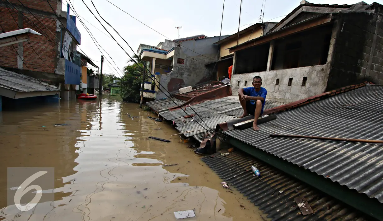 Warga berada di atap rumahnya di kawasan Perumahan Pondok Gede Permai, Bekasi, Jawa Barat, Kamis (21/4). Banjir dengan ketinggian tiga meter yang berasal dari meluapnya Sungai Cikeas. (Liputan6.com/ Immanuel Antonius)