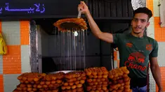 Seorang pria menjajakan kue manis khas Aljazair jelang Ramadan, di Aljir, Jumat (26/5). Kue-kue dengan rasa manis umum ditemukan sebagai menu untuk berbuka puasa. (AP Photo / Anis Belghoul)