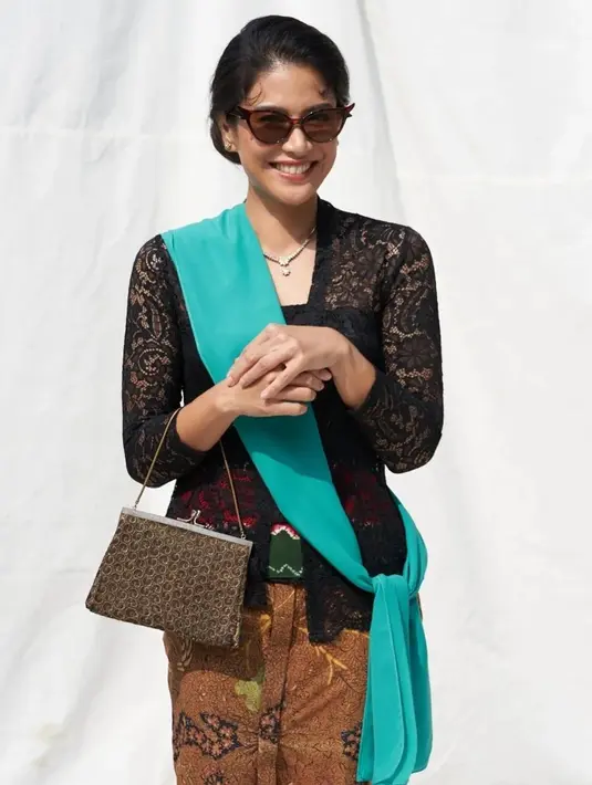 Dalam nuansa yang lebih gelap, Dian Sastro memilih mengenakan kebaya brokat hitam, yang dipadunya dengan kain batik sebagai bawahan. Di bagian pinggang, kain berwarna hijau tua digunakan sebagai innerwear, dan ia menyampirkan selendang biru cerah, lengkap dengan hand bag, dan sunglasses. Foto: Instagram.