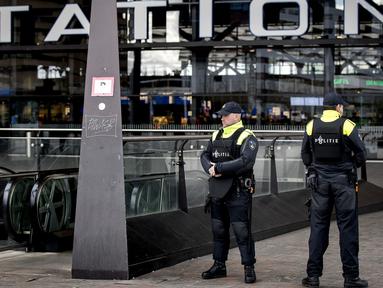 Aparat kepolisian berjaga di pintu masuk sebuah stasiun di Rotterdam, Senin (18/3). Pihak keamanan di Belanda meningkatkan keamanan di bandara dan bangunan penting lainnya usai penembakan di Utrecht yang menewaskan 3 orang.  (KOEN VAN WEEL/ANP/AFP)