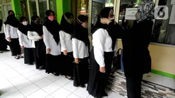 Peserta diperiksa seluruh badannya sebelum pelaksanaan ujian seleksi kompetensi P3K Guru di SMKN 2, Depok, Jawa Barat, Selasa (14/9/2021). Kemendikbud mulai Senin (13/9) secara serentak di Indonesia dilaksanakan ujian Seleksi Kompetensi P3K yang tersebar di 1000 lokasi. (merdeka.com/Arie Basuki)