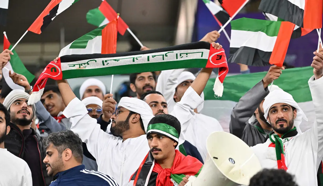 Suporter melambaikan bendera sebelum dimulainya pertandingan sepak bola Grup C Piala Asia AFC Qatar 2023 antara Palestina dan Uni Emirat Arab di Stadion Al-Janoub di Al-Wakrah, Doha pada 18 Januari 2024. (HECTOR RETAMAL/AFP)