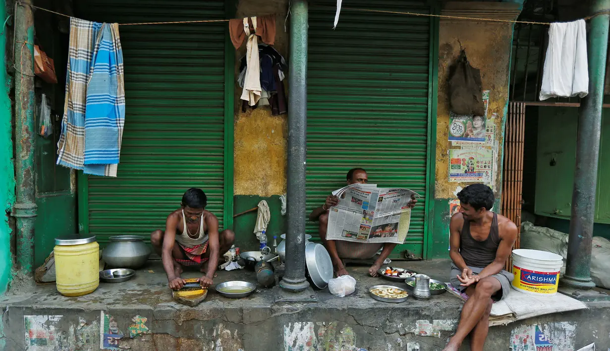 Sejumlah pekerja mempersiapkan makan pagi dan membaca koran di depan toko di Kolkata, India (26/5/2016). Kolkuta ialah ibu kota India antara 1833 sampai 1912  Terdapat Universitas Kolkata dan Museum India. (REUTERS/Rupak De Chowdhuri)