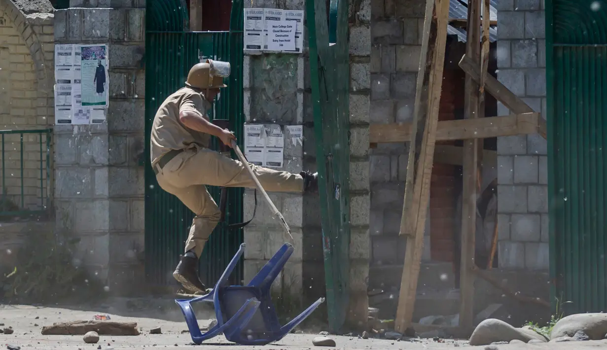 Polisi India menendang gerbang sebuah perguruan tinggi di Srinagar, Kashmir yang dikuasai India, (23/5). Bentrokan telah meningkat setelah tentara menggerebek sebuah perguruan tinggi di kota selatan Pulwama bulan lalu. (AP Photo/Dar Yasin)