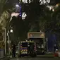 Petugas kepolisian berdiri di dekat  sebuah truk yang menabrak kerumunan orang di Nice, Prancis, Kamis (14/7). Truk itu melaju cepat dengan target kerumunan massa yang menyaksikan pesta kembang api dalam perayaan Bastile Day. (VALERY HACHE/AFP)