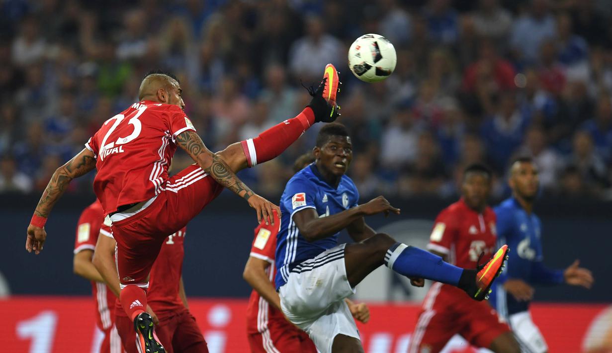 Pemain Bayern Munchen, Arturo Vidal, berebut bola dengan pemain Schalke 04, Abdul Rahman Baba, dalam lanjutan Bundesliga di Veltins Arena, Gelsenkirchen, Sabtu (10/9/2016) dini hari WIB. (AFP/Patrik Stollarz)