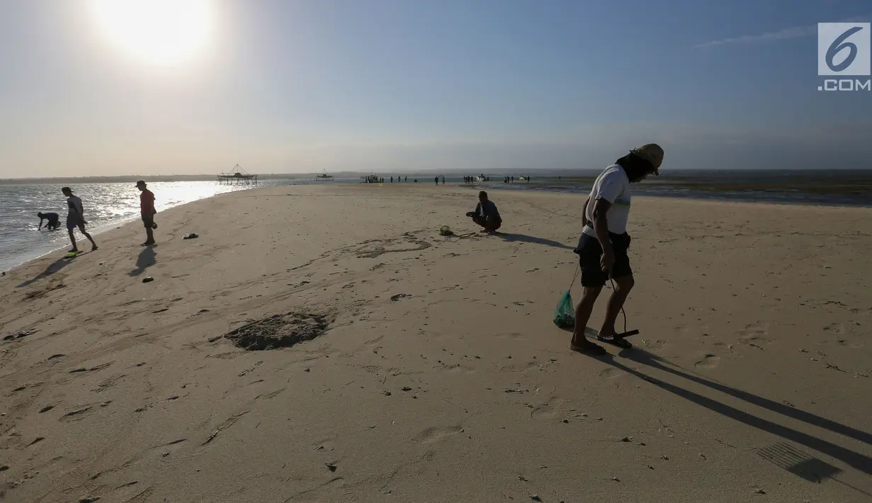 Warga berjalan di pesisir pantai Pulau Pasir, Lombok Timur, Sabtu (3/8/2019). Mereka mulai menangkap kerang ketika Pulau Pasir yang membentang laut akan tampak ketika air laut surut. (Liputan6.com/Fery Pradolo)