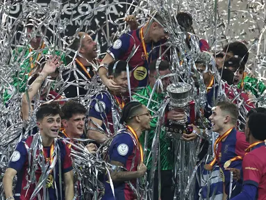 Para pemain Barcelona merayakan kemenangan dengan trofi setelah pertandingan final Piala Super Spanyol 2025 melawan Real Madrid di King Abdullah Sport City, Jeddah pada Senin (13/1/2025) dini hari WIB. (FADEL SENNA/AFP)