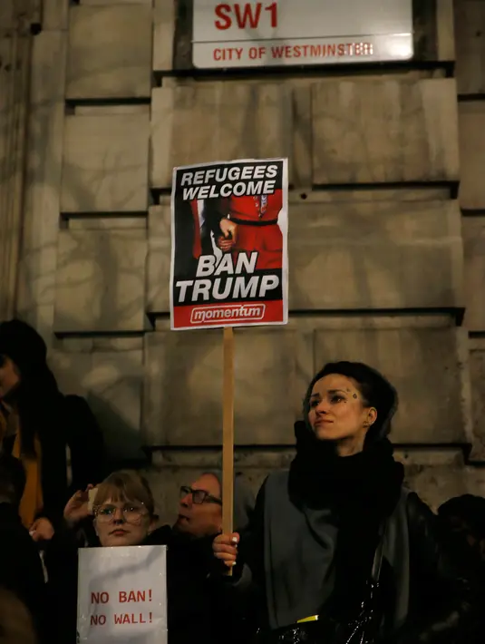 Pengunjuk rasa membawa poster saat bergabung ikut dalam unjuk rasa di luar Downing Street, London, Senin (30/1). Mereka memprotes kebijakan Presiden Donald Trump yang melarang Muslim dari sejumlah negara memasuki Amerika Serikat. (AP Photo/Alastair Grant)