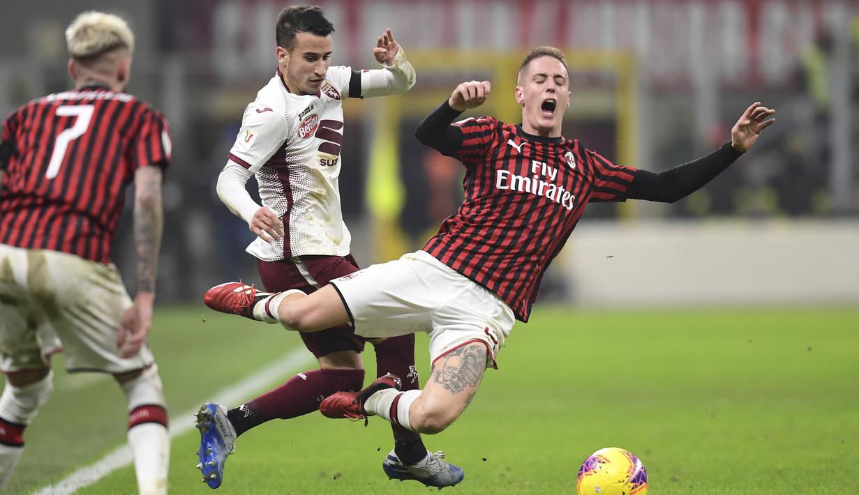 Bek AC Milan, Andrea Conti, dijatuhkan striker Torino, Alex Berenguer, pada laga Coppa Italia di Stadion San Siro, Milan, Selasa (28/1). Milan menang 4-2 atas Torino. (AFP/Miguel Medina)