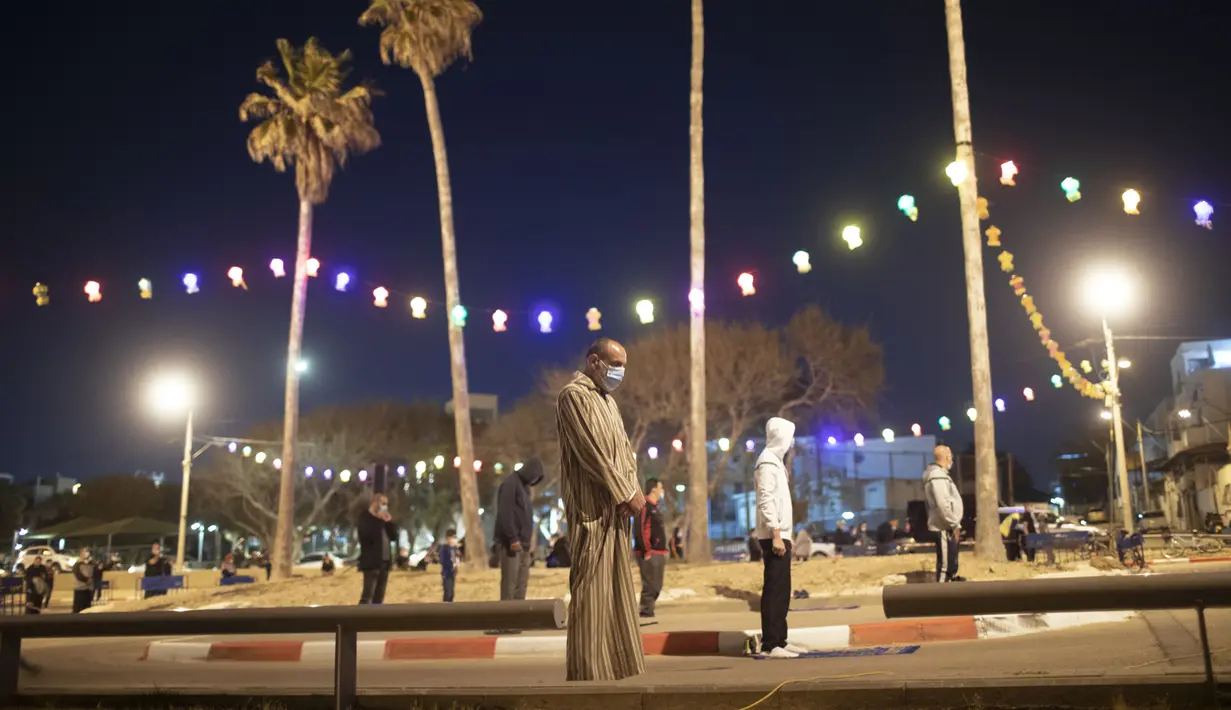 Umat muslim menerapkan jaga jarak aman saat melaksanakan salat tarawih di sebuah tempat parkir di kota campuran Yahudi-Arab, Jaffa, Israel, Minggu (10/5/2020). Israel menutup tempat umum dan rumah ibadah untuk mencegah penyebaran virus corona COVID-19. (AP Photo/Oded Balilty)