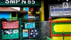 Suasana gerbang Sekolah Menengah Pertama (SMP) Negeri 85 yang ditutup di Pondok Labu, Cilandak, Jakarta, Rabu (27/7/2022). Sekolah tersebut ditutup selama 10 hari setelah tiga siswa terkonfirmasi COVID-19. (Liputan6.com/Johan Tallo)
