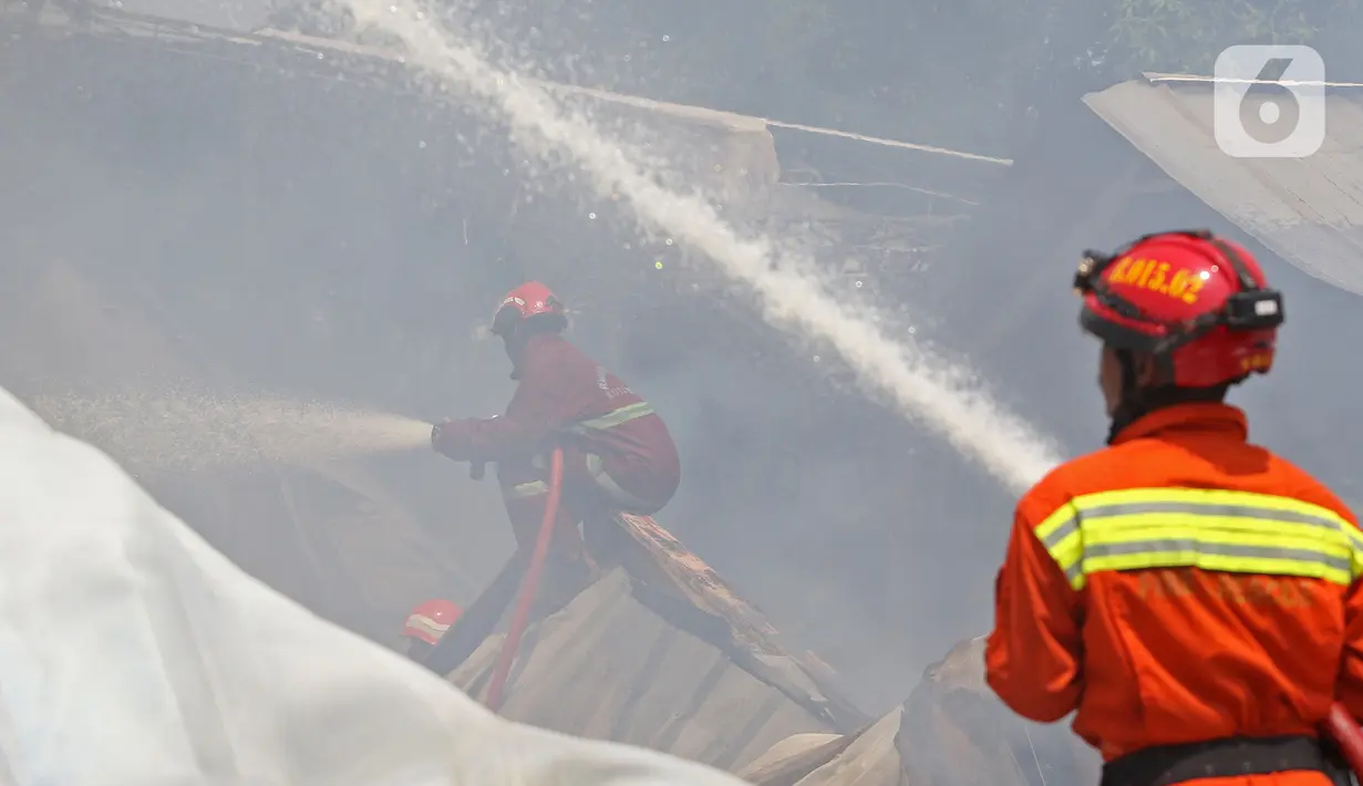 Petugas pemadam kebakaran memadamkan api yang membakar gudang alat pesta di kawasan Cinangka, Depok, Senin (2/8/2021). Banyaknya bahan dari kayu serta bahan yang mudah terbakar, membuat api dengan cepat menyambar dan menghanguskan isi dan bangunan gudang. (Liputan6.com/Herman Zakharia)