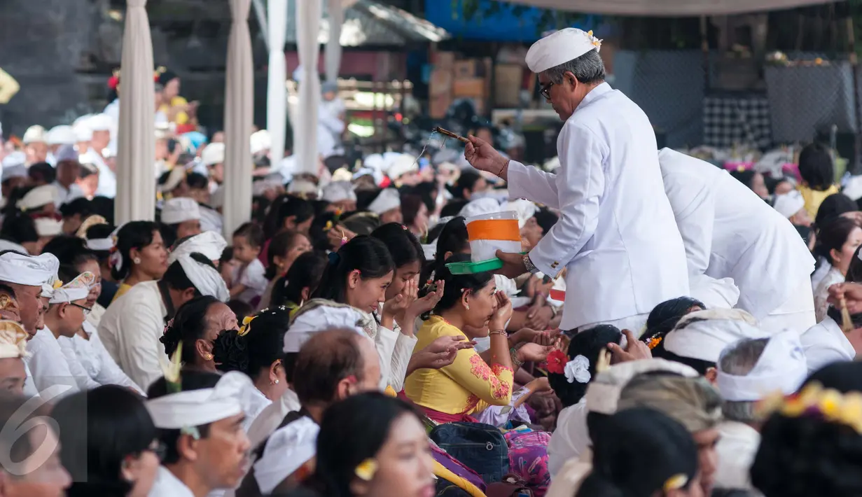 Pemangku menyipratkan air suci pada umat Hindu dalam prosesi Tawur Agung Kesanga menjelang Hari Raya Nyepi di Pura Aditya Jaya, Jakarta, Senin (27/3). Tawur Agung Kesanga ini merupakan upacara yang membersihkan alam semesta. (Liputan6.com/Gempur M Surya)