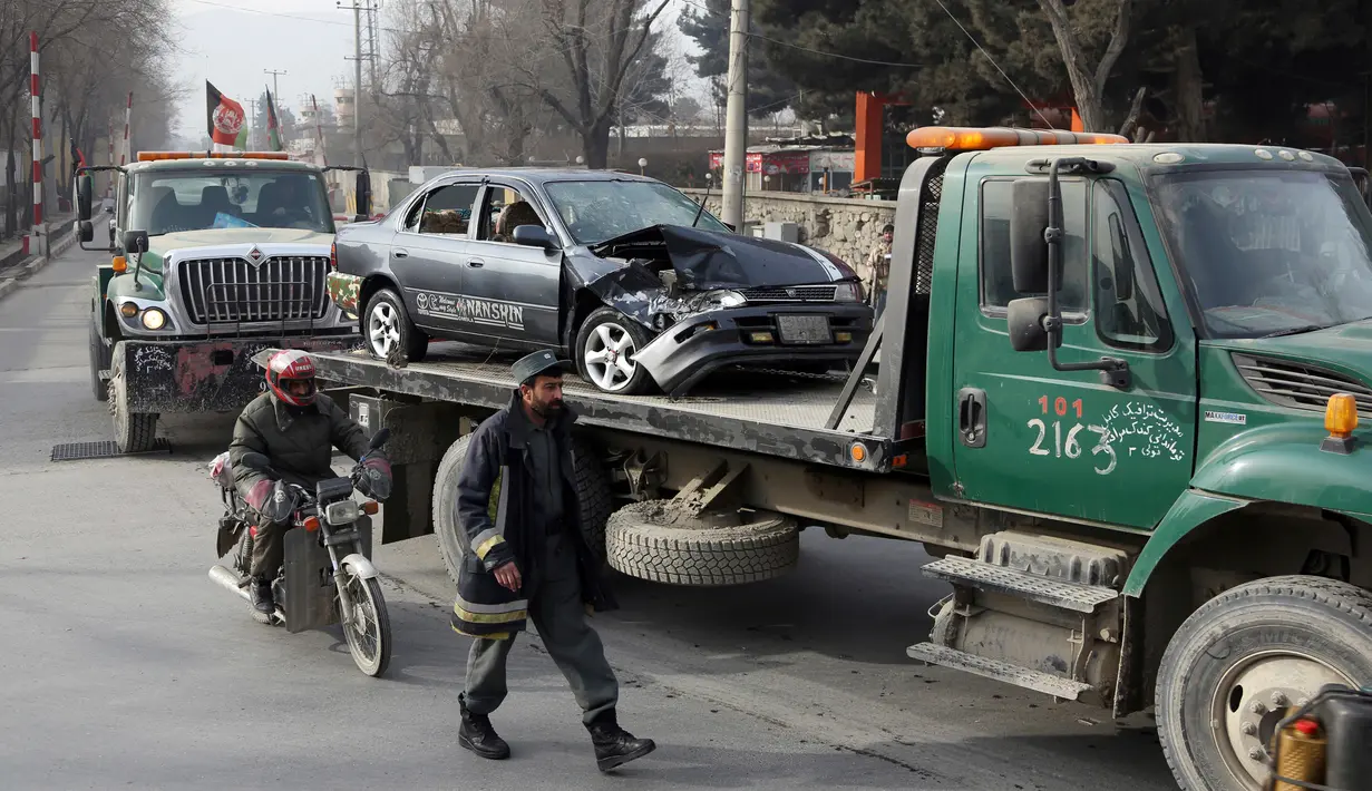 Pasukan keamanan Afghanistan memindahkan sebuah mobil yang hancur akibat terkena serangan bom bunuh diri di Kabul, Afghanistan (25/12). Bomber tersebut melancarkan serangannya saat para pekerja tiba di kantor mereka. (AP Photo / Rahmat Gul)