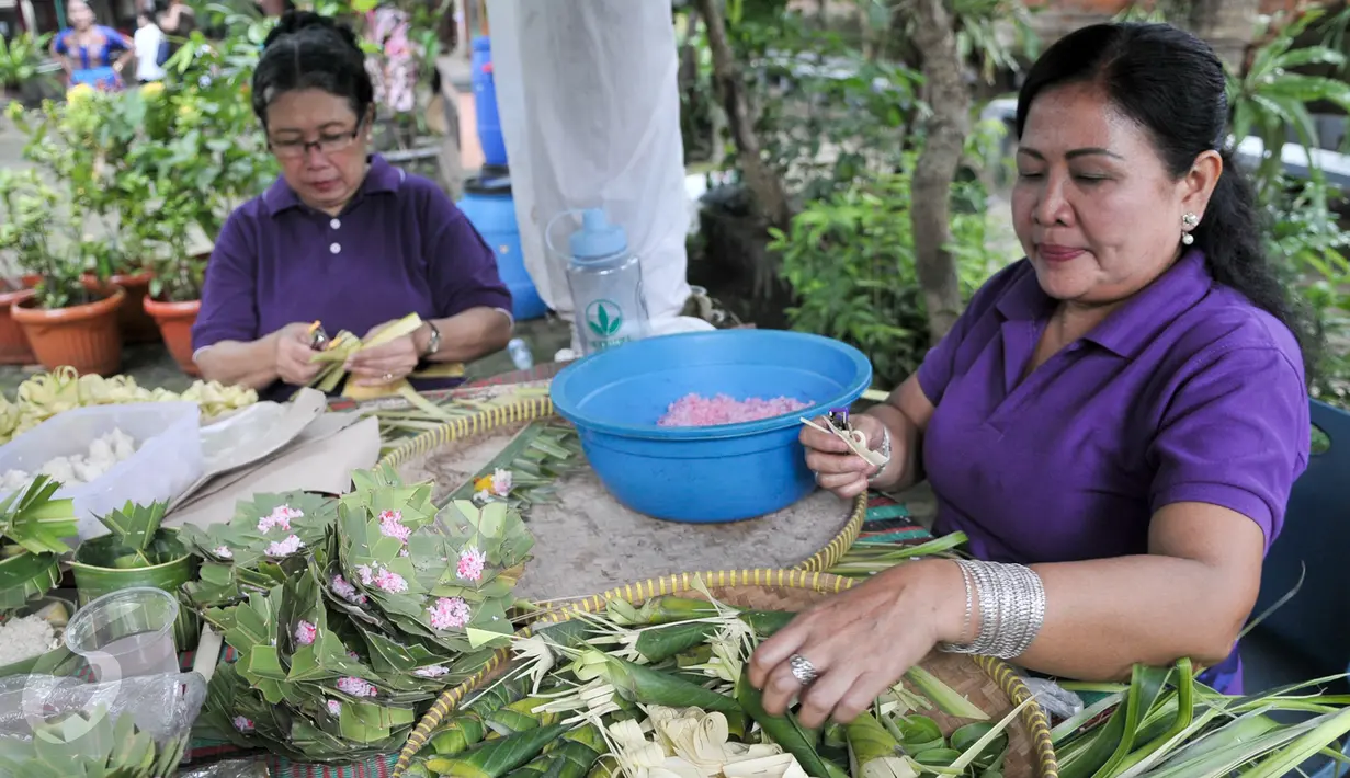Umat Hindu membuat sesajen jelang perayaan Nyepi di Pura Aditya Jaya, Jakarta, Sabtu (25/3). Sesajen tersebut merupakan simbol persembahan kepada Sang Hyang Widhi Wasa atau Sang Pencipta sebagai bentuk syukur jelang Nyepi. (Liputan6.com/Yoppy Renato)